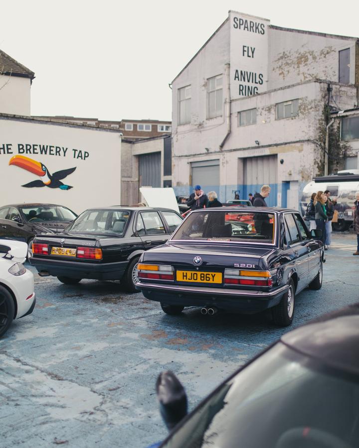 BMW 325i and 520i parked under the Sparks Fly sign