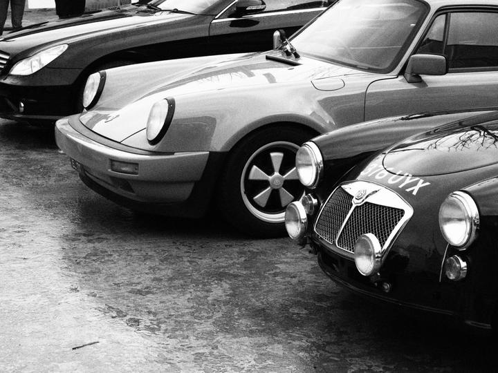 Porsche 911 Carrera next to a rally-prepared MGA, in black and white