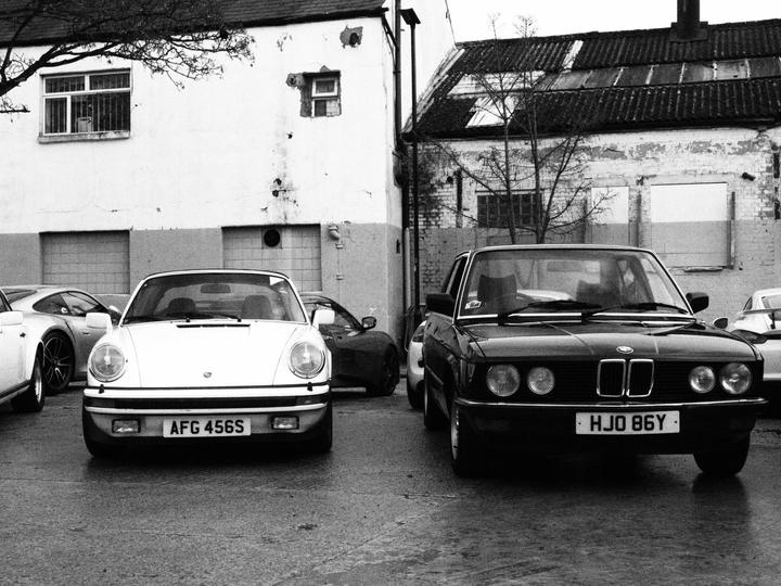 Porsche 911 SC and BMW E28 side by side, in black and white