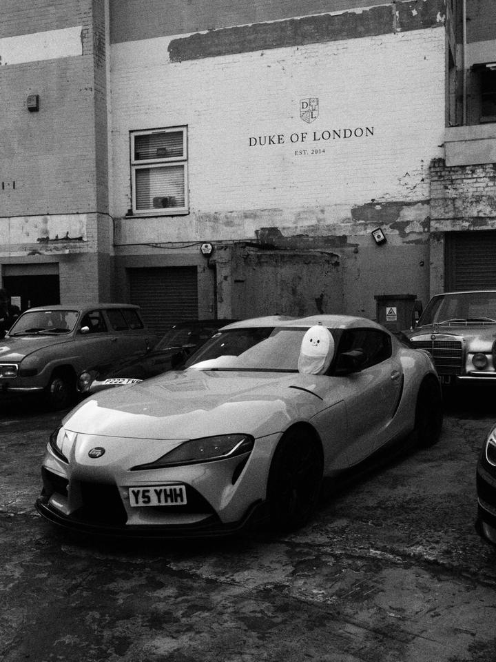 Toyota Supra under the Duke of London sign, with a soft toy on the windscreen