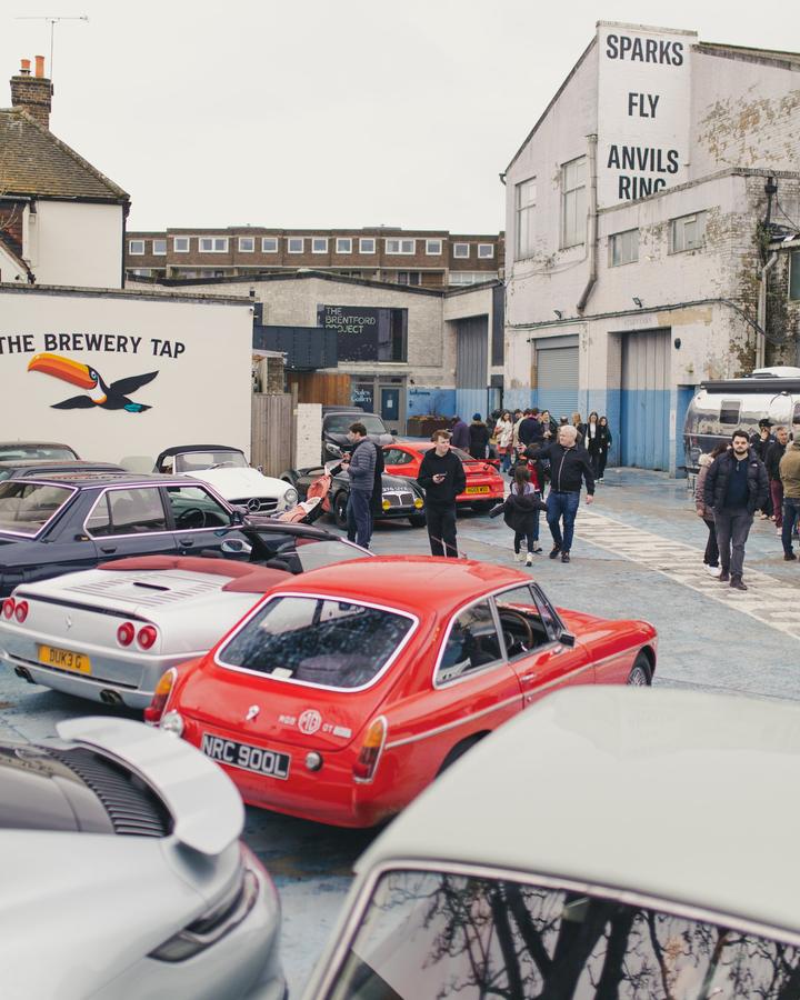 The yard at Duke of London: MGB GT, Ferrari F355, Mercedes 190 SL and the crowd under the Sparks Fly sign