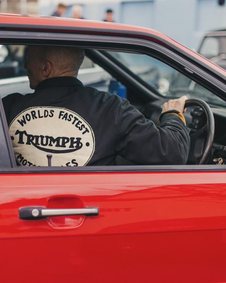 Driver in a Triumph motorcycles jacket at the wheel