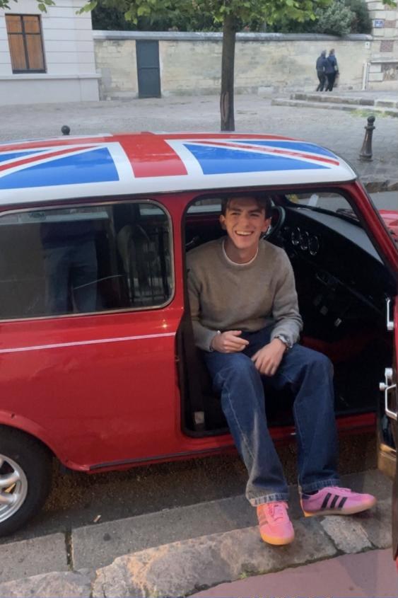 Alec Deneef-Matthews sitting in his red classic Mini with a Union Jack roof